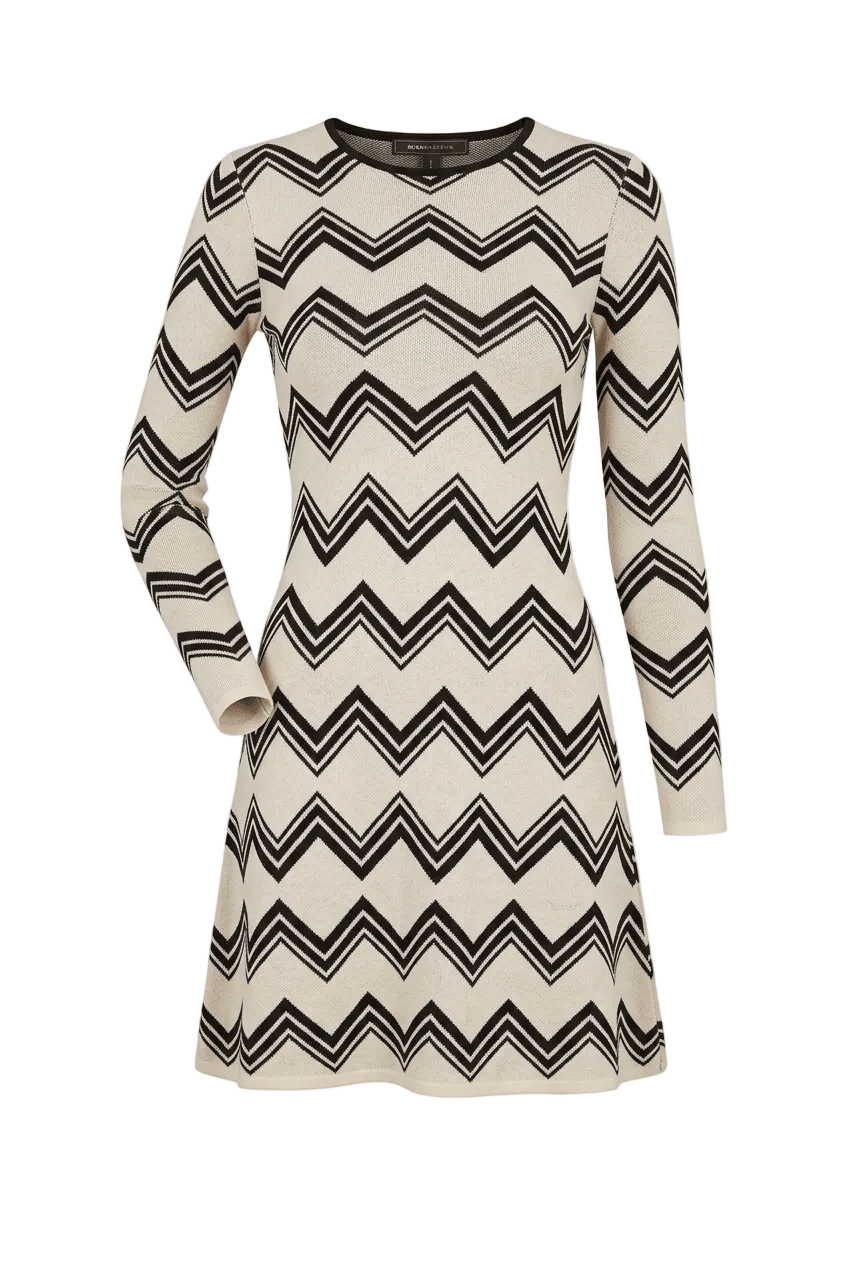 A long-sleeve knit dress with a black and off-white chevron pattern, shown against a light beige background.