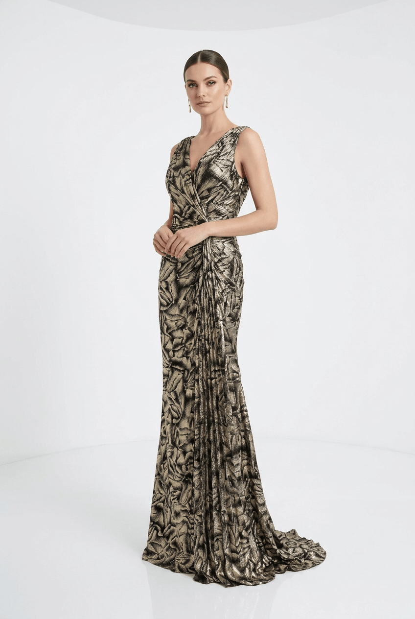 A woman modeling a floor-length sleeveless gown with a metallic gold and black abstract pattern, set against a clean white studio background.