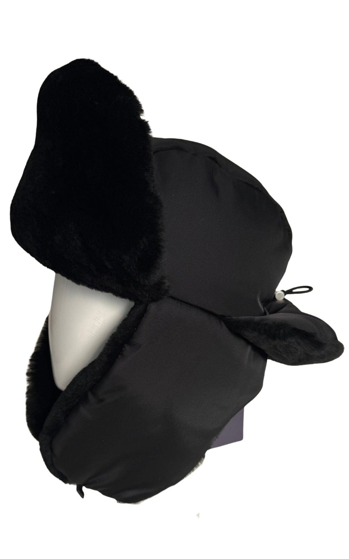 A black Prada winter trapper hat with plush faux-fur ear flaps and chin coverage, displayed on a white mannequin head against a plain white background.