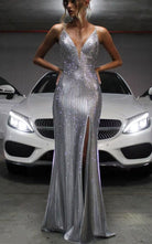 Silver rhinestone mermaid formal dress v plunge front view on a model posing in front of a Mercedes